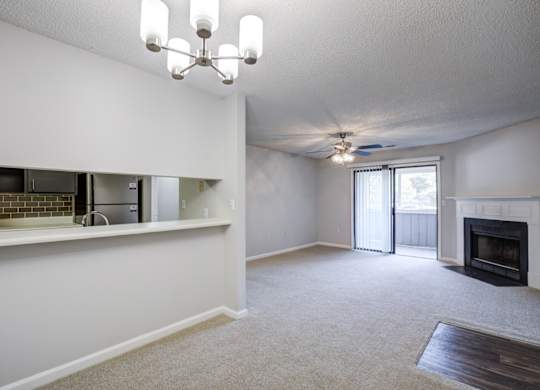 A living room with a fireplace and a ceiling fan at Southland Station Apartments in Warner Robins, 31088