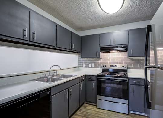 A kitchen with black cabinets and stainless steel appliances at Southland Station Apartments in Warner Robins, GA
