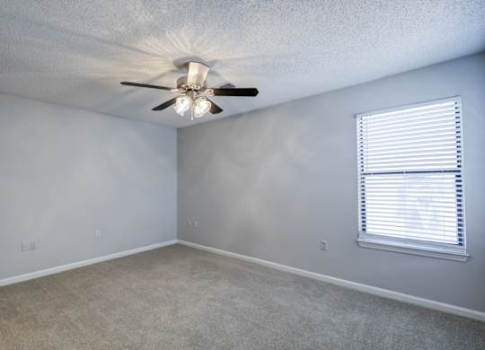 A room with a ceiling fan and a window with blinds at Southland Station Apartments in Georgia, 31088