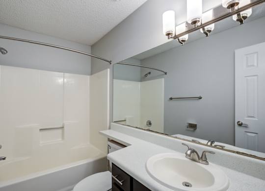 A white bathroom with a toilet, sink, and bathtub at Southland Station Apartments in Warner Robins, GA
