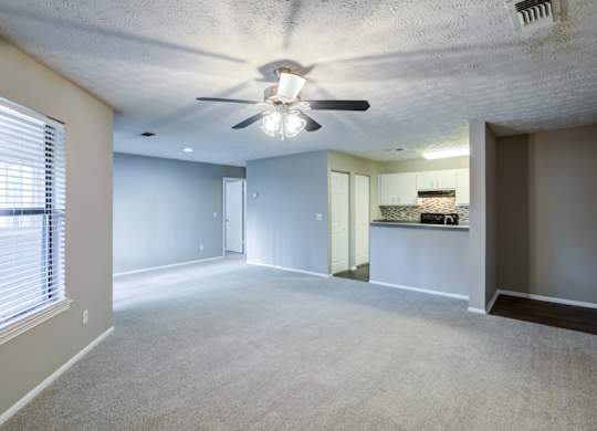 A spacious room with a ceiling fan and a window with blinds at Southland Station Apartments in Warner Robins, 31088