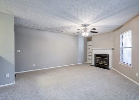 A living room with a fireplace and a ceiling fan at Southland Station Apartments in Georgia, 31088