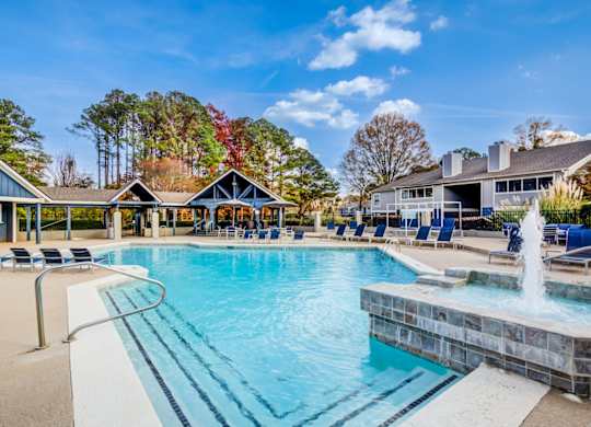 A large swimming pool with a fountain in the middle of it at Southland Station Apartments in GA, 31088