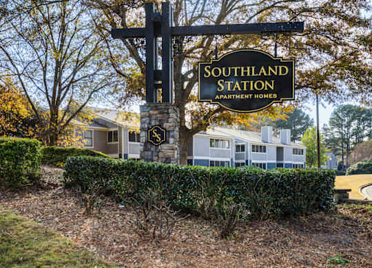 A sign for Southland Station Apartment Homes stands in front of a building at Southland Station Apartments in Warner Robins, GA, 31088