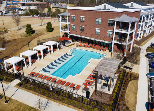 an aerial view of the resort style pool with red lounge chairs and umbrellas at The Flats at Southlawn Apartments, Lawrenceville, 30046