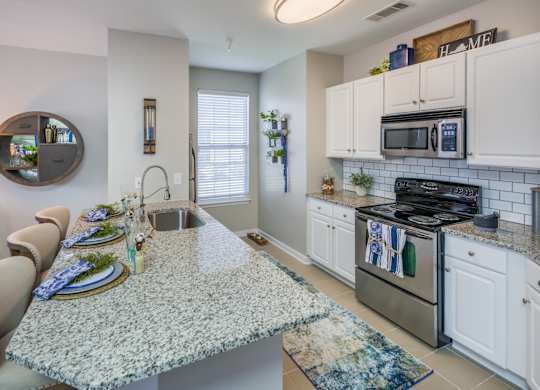 A kitchen with granite countertops and white cabinets.