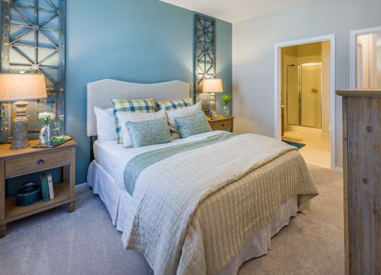 A bedroom with a bed, nightstand, and a wooden cabinet.