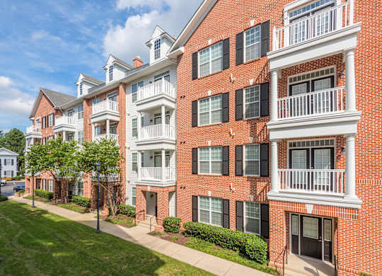 A red brick apartment building with white balconies and black shutters.