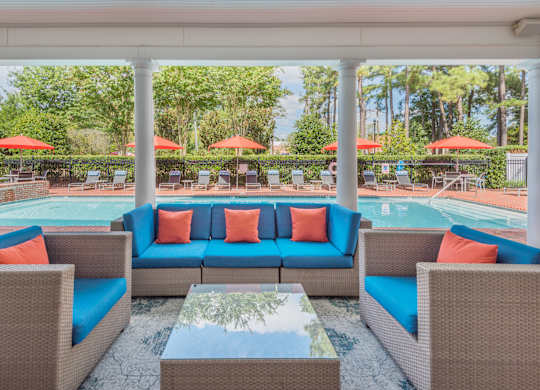 A patio with a pool and a table with chairs.
