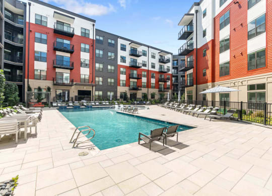 an outdoor pool with lounge chairs and tables at the bradley braddock road station apartments at Tapestry West, Virginia, 23230
