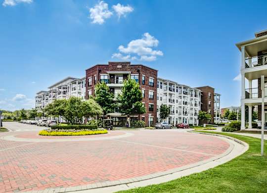 A large brick building with a white building to the right and a green lawn in front.