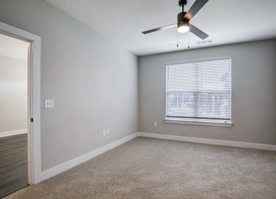 A room with a ceiling fan and a window with blinds.
