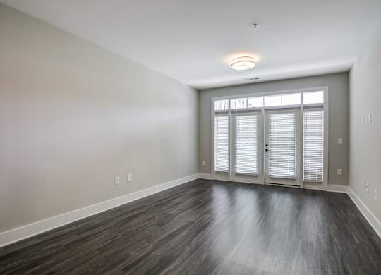 A room with wooden flooring and a window with blinds.