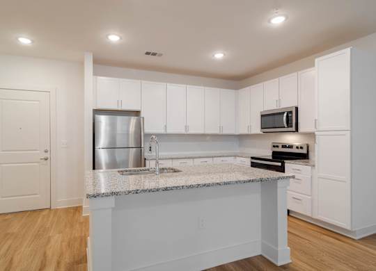 A kitchen with white cabinets and a granite countertop.