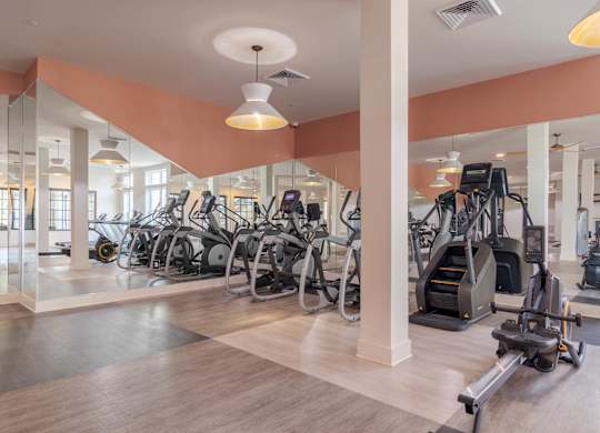 A gym with a variety of exercise equipment including treadmills, stationary bikes, and elliptical machines.