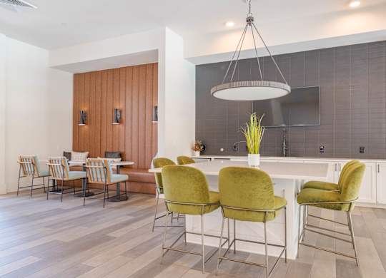 A kitchen with a bar area and green chairs.