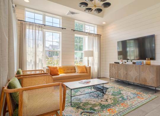 A living room with a sofa, chairs, and a rug.