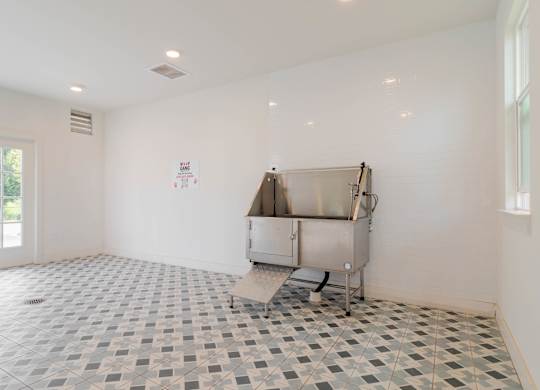 A large empty room with a tiled floor and a stainless steel appliance.