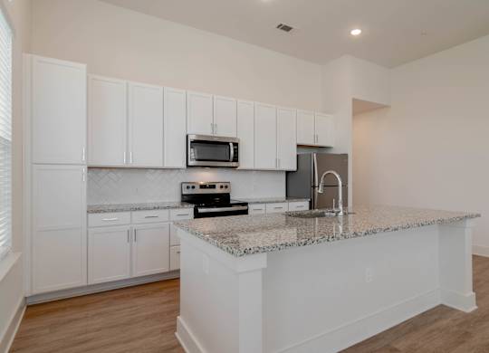 A kitchen with white cabinets and a granite countertop.