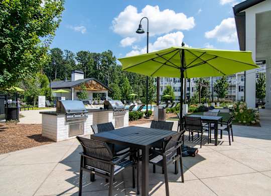 A patio with a table and chairs under a yellow umbrella.