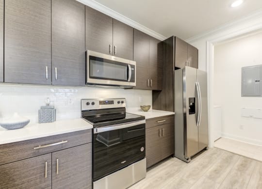 a modern kitchen with stainless steel appliances and dark wood cabinets at Residences at 393 North Apartments, Santa Rosa Beach, FL