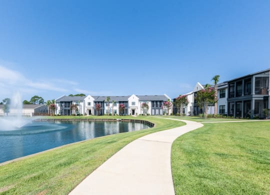 a sidewalk next to a lake with apartments in the background at Residences at 393 North Apartments, Santa Rosa Beach