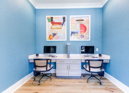 two desks with two monitors and two chairs in a room with blue walls at Residences at 393 North Apartments, Santa Rosa Beach
