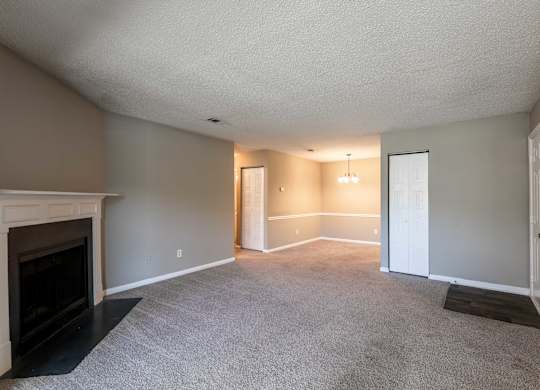 A living room with a fireplace and carpeted floor.