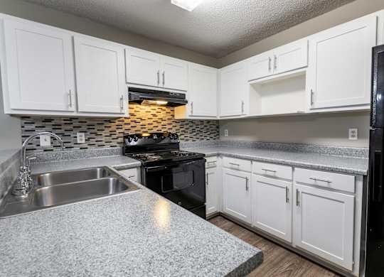 A kitchen with white cabinets and a black refrigerator.