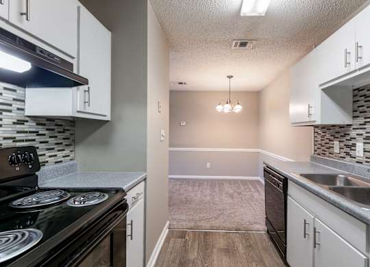 A kitchen with a black stove top oven and white cabinets.