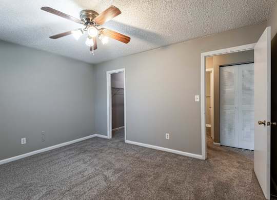 A room with a ceiling fan and carpeted floor.
