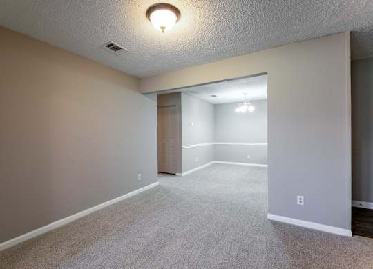 A room with a carpeted floor and a doorway leading to another room.