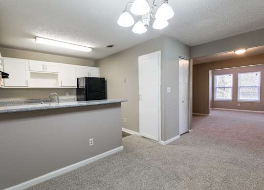 A kitchen with white cabinets and a black refrigerator.