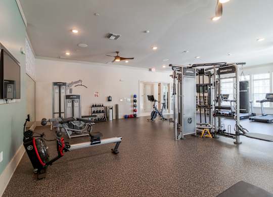 A spacious gym with a variety of equipment including a treadmill, a bench press, and a squat rack.