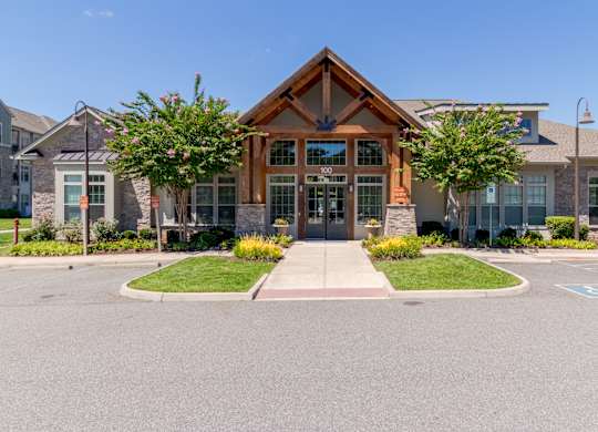A building with a brown roof and a glass door is surrounded by a grassy area and a paved walkway.