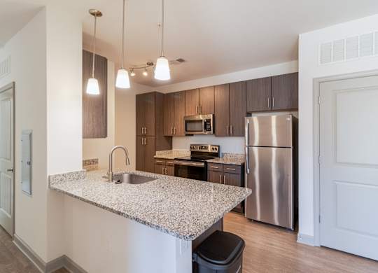 A kitchen with a granite countertop and stainless steel appliances.