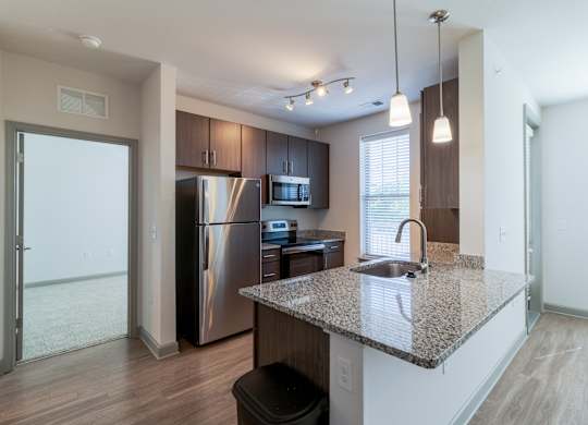 A kitchen with a granite countertop and stainless steel appliances.
