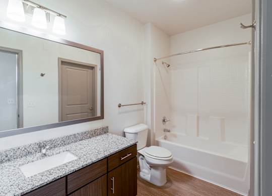 A white toilet sits in a bathroom next to a sink and a bathtub.