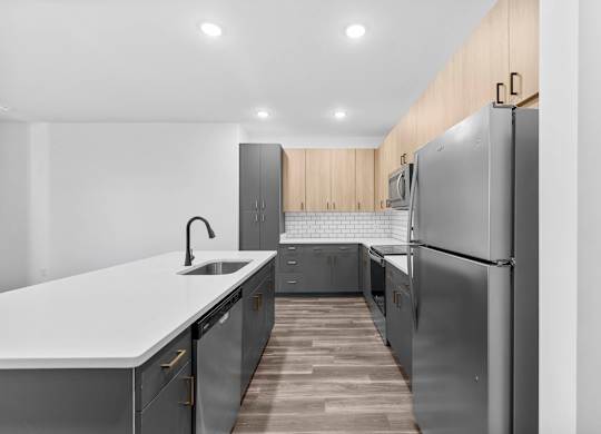 A modern kitchen with a white countertop and stainless steel appliances.