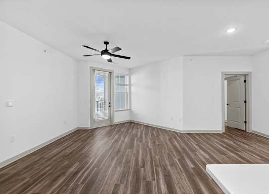 A room with a ceiling fan and wooden flooring.