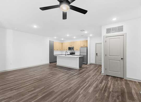 A room with a ceiling fan and wooden flooring.