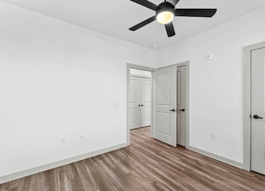 A room with a ceiling fan and wooden flooring.