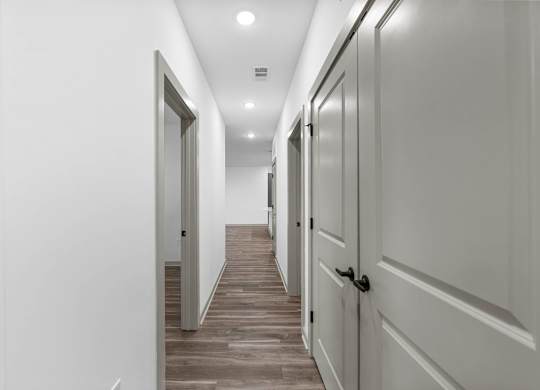 A long hallway with white walls and wood floors.