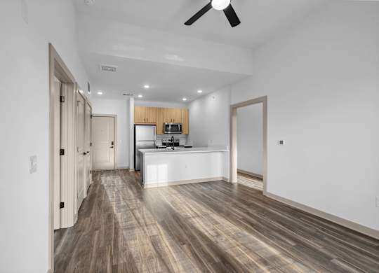A modern kitchen with wooden floors and a ceiling fan.