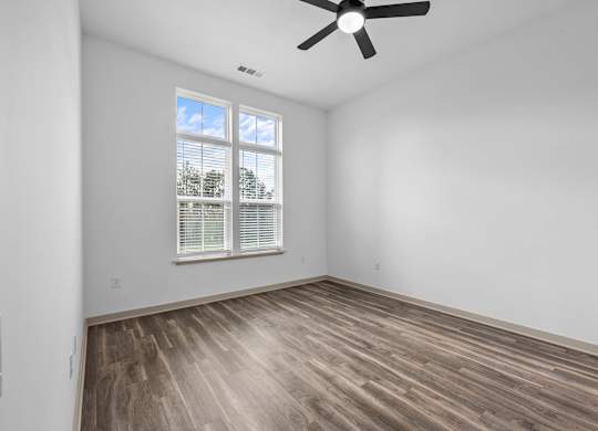 A room with a ceiling fan and a window with blinds.
