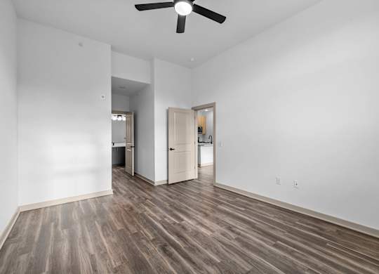 A room with a ceiling fan and wooden flooring.