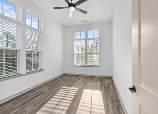 A room with a ceiling fan and wooden flooring.