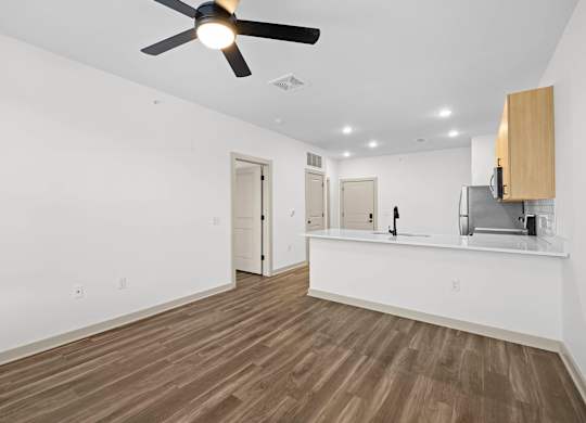 A room with a ceiling fan and wooden flooring.
