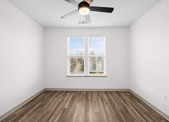 A room with a ceiling fan and a window with blinds.