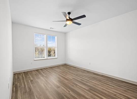 A room with a ceiling fan and wooden flooring.